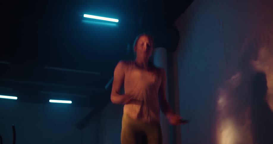 Woman with ponytail and shirt and shorts jumps rope in the gym