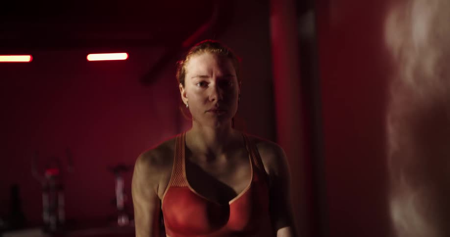 A woman is standing in a gym walking on a treadmill