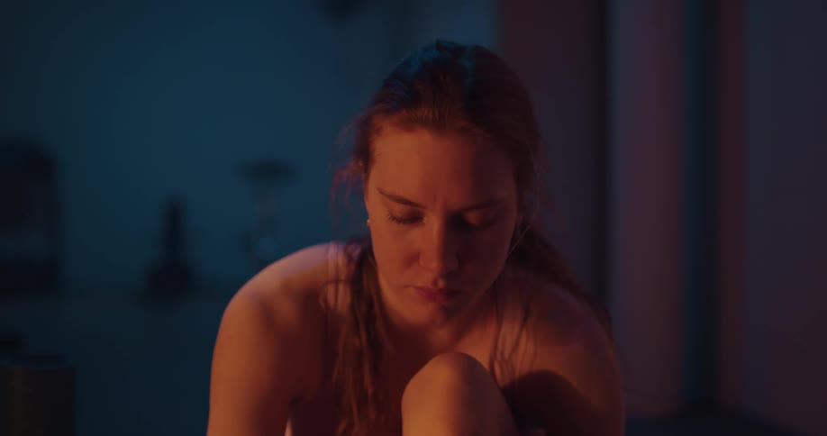 A woman is sitting on the floor tying her shoes
