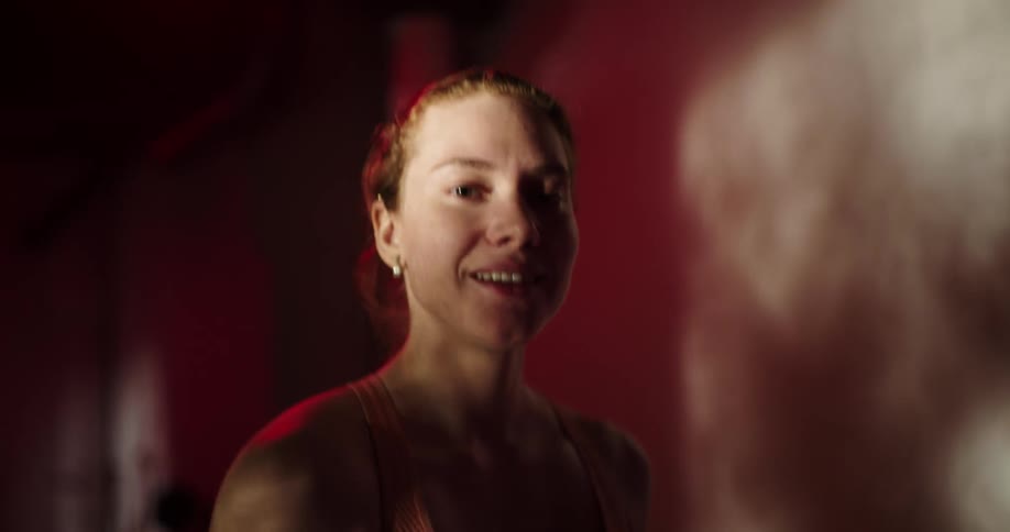 A woman in a sports bra smiling while walking on a treadmill