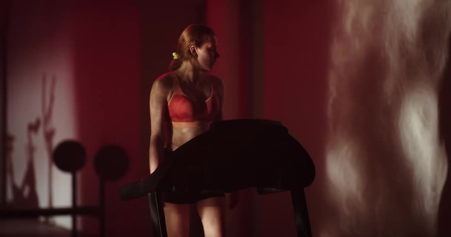 A woman in a sports bra walking on a treadmill in a fitness room