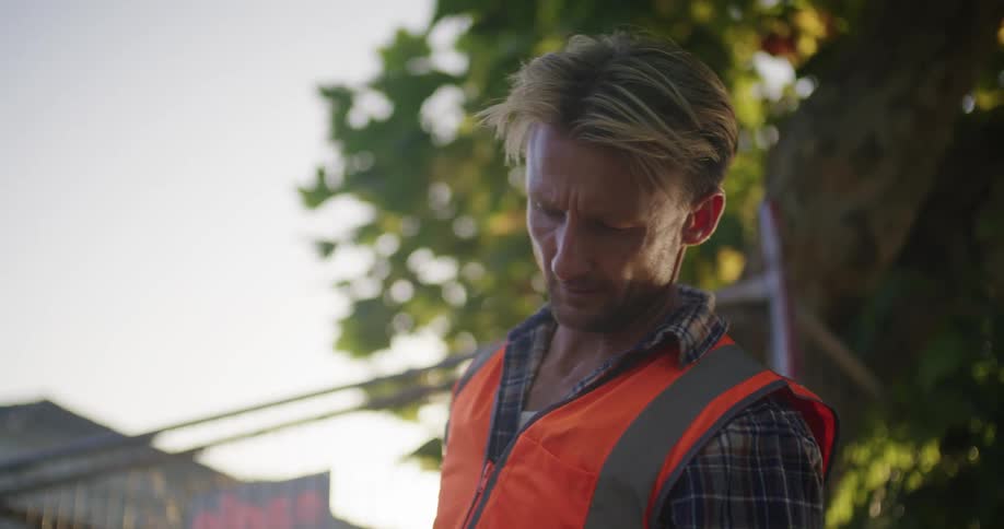 A man hammers a for sale sign outside a foreclosed property under construction