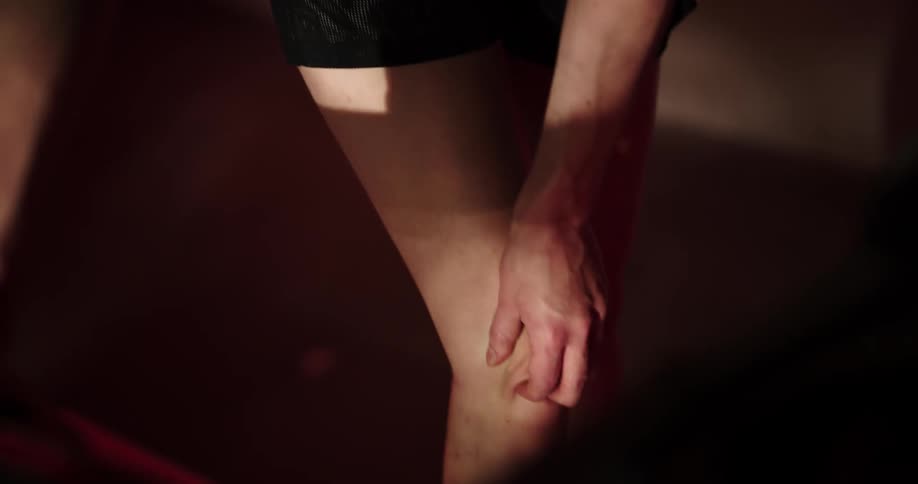Woman wearing shorts rubs her leg as it is sore on treadmill at the gym