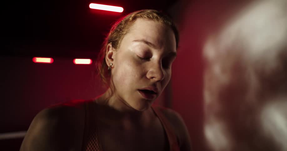 A woman breathing heavily and wiping her forehead while exercising on a treadmill