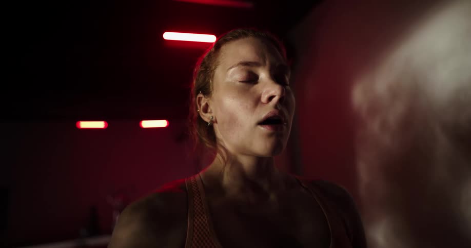 A woman sweats as she is breathing hard then smiles