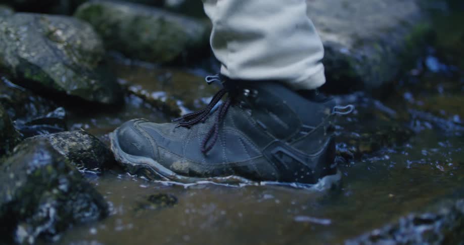 Person steps through running water while hiking