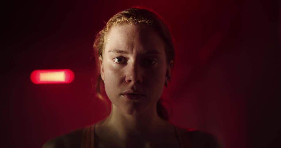 A woman walking on a treadmill in a dimly lit room