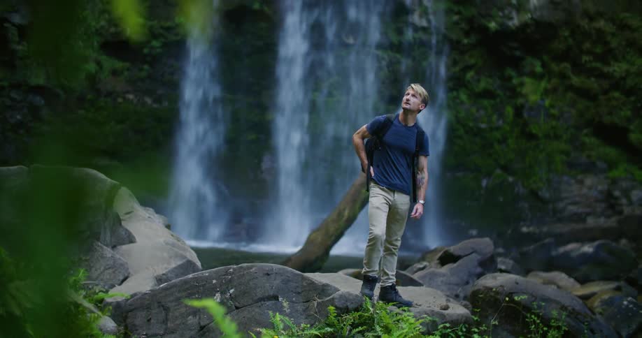 A man is hiking by the waterfall