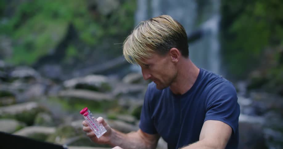 A scientist collecting water samples from a river in nature and logging data