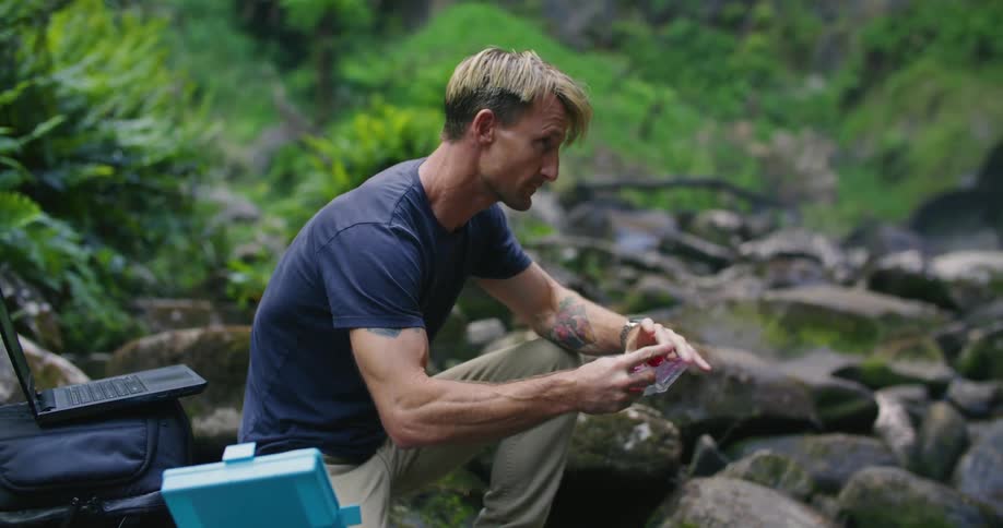 A male scientist taking a water sample from a river in nature