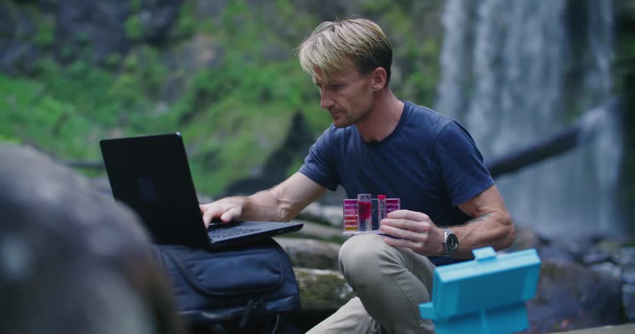 A man is using a kit to test stream water