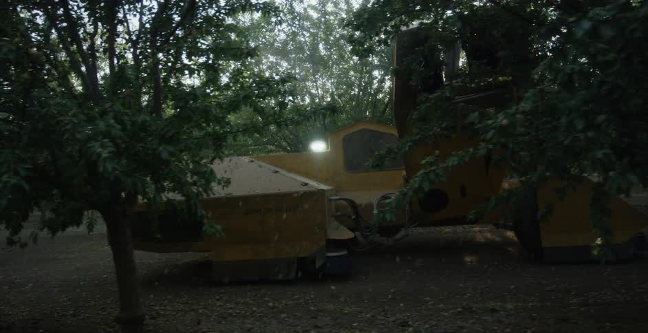 A combine carries a wooden structure through the woods
