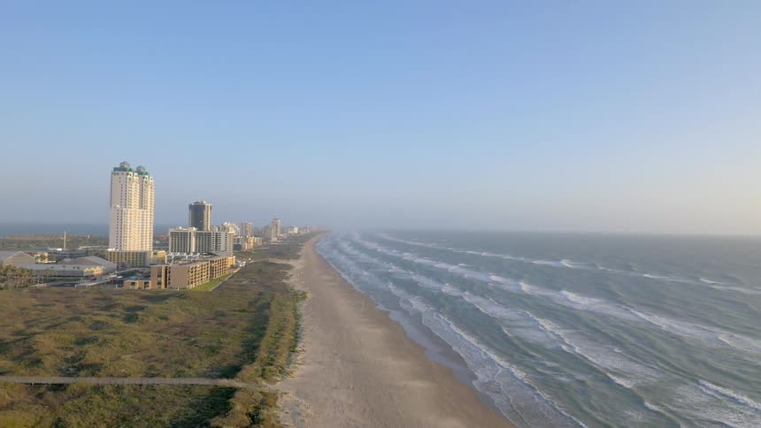 Waves roll in on a beach near a city