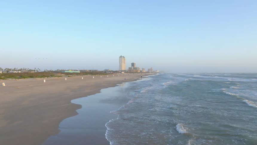 Waves roll onto a beach near a city