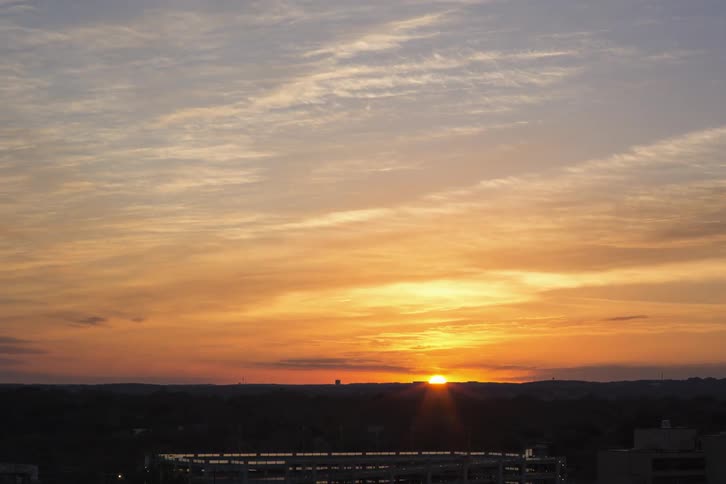 Clouds streaming across a mountainous area as the sun sets