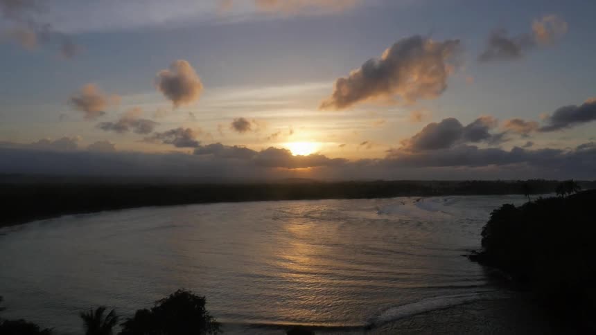 Flying over a tropical area to the water during sunset