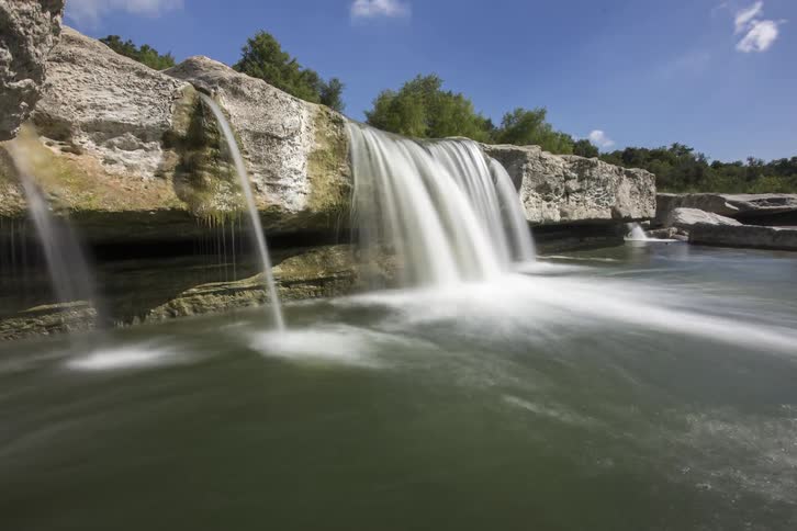Water flows and over the edge of some rocks creating several waterfalls