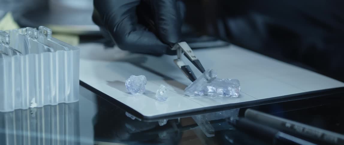 A lab worker uses tweezers to place items on a tabletop