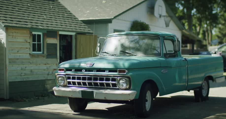 A vintage pickup truck is parked in the driveway of a home