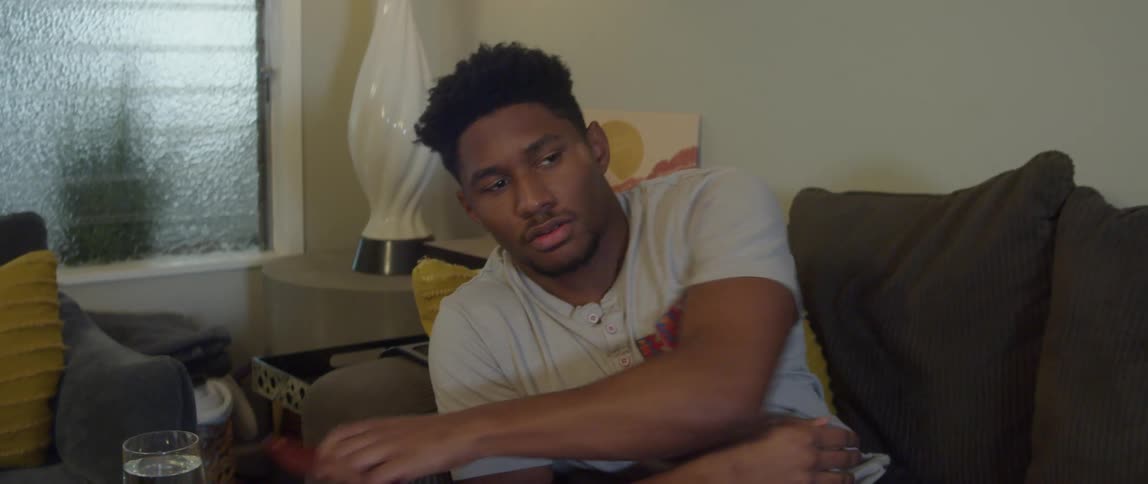 Man sitting on couch watching television turns to respond to his smartphone