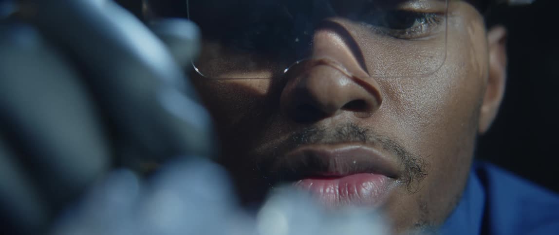 Craftsman works on crystalline chunk while viewing it through magnifying glasses