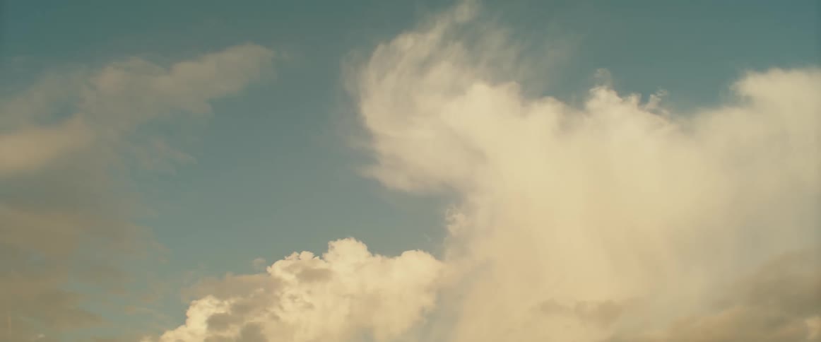 Dense fluffy clouds fill the sky as the sun is setting