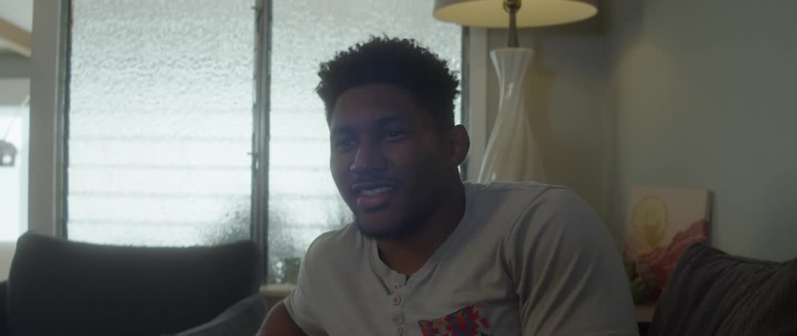 A man starts laughing as he sits on his couch