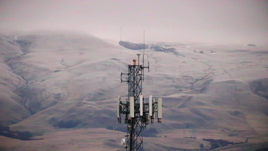 Aerial view of cell tower carrying antennas with snowy mountains in the background