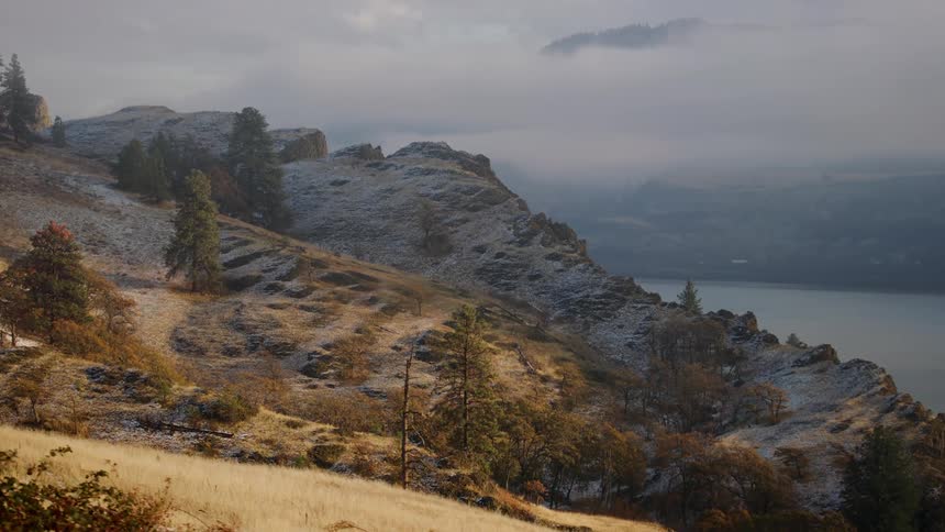 Looking into a massive river canyon with dried tan grass on the hillside driving on the way to Thanksgiving dinner in November with snow on the ground