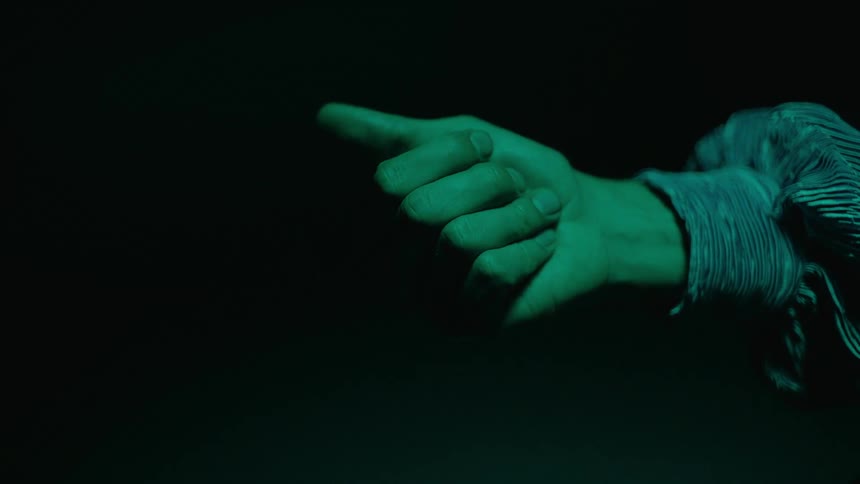 Light shines on a persons open hand with a small disk in their palm as they close their fingers and make a fist