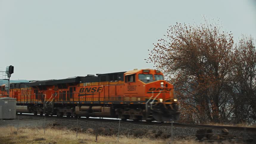 Freight train carrying goods runs along railway track near the Columbia River