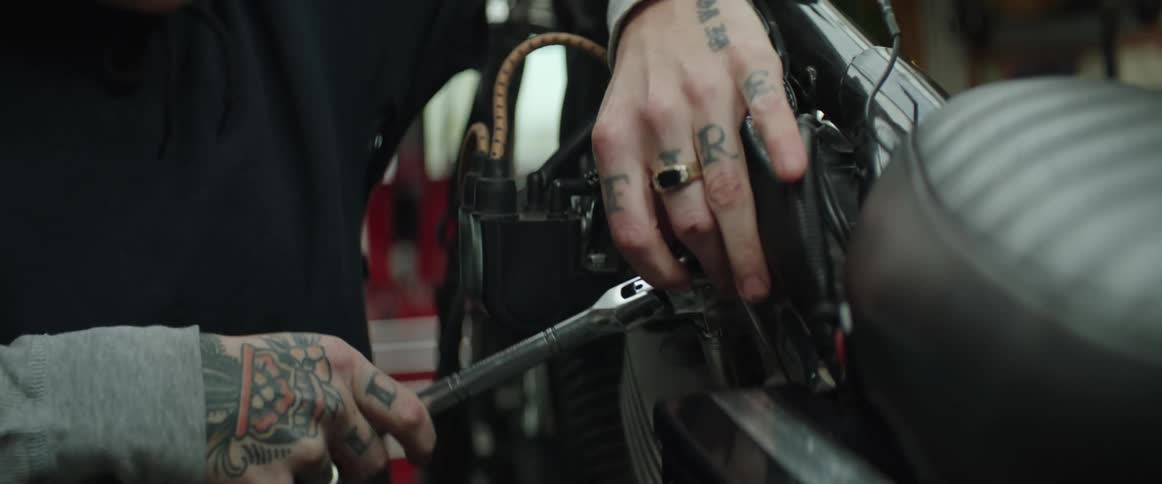 A person's hands using a wrench to tighten a bolt on a motorycle
