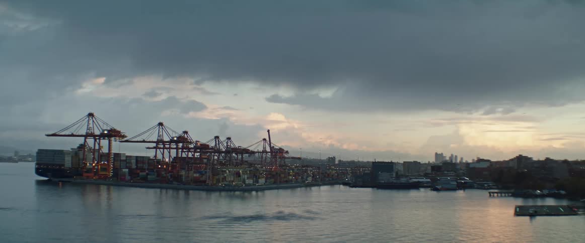 Stacks of shipping containers on waterfront dock at sunrise