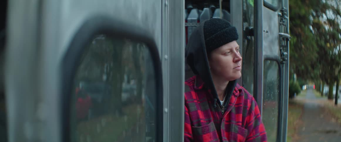 A person texts on their phone while sitting in the back of a truck
