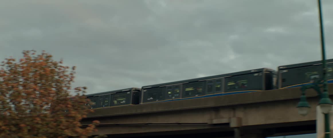 Skytrain runs along railway track on overpass towards downtown Vancouver