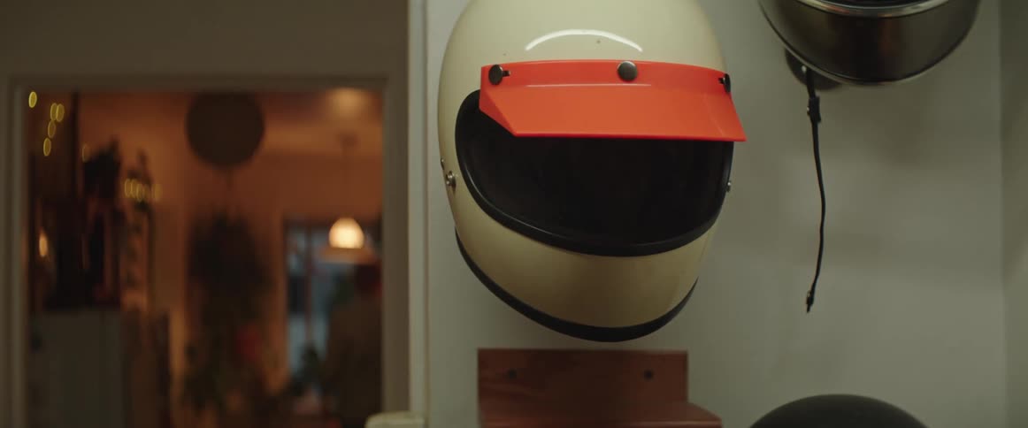 A white and orange motorcycle helmet hanging on a wall