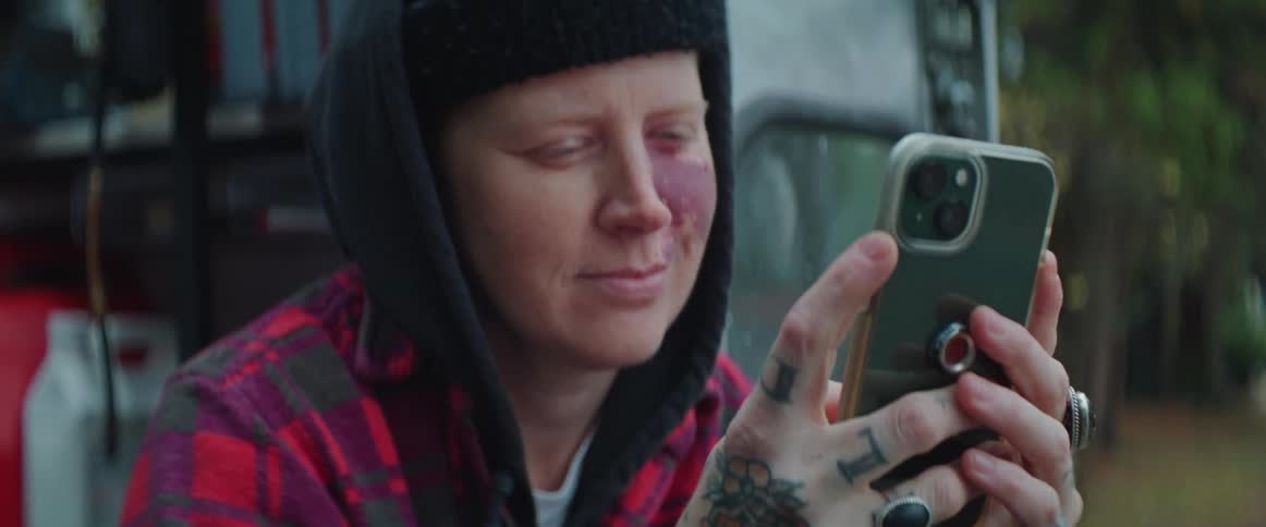 A woman scrolls through her phone while sitting in the back of his truck