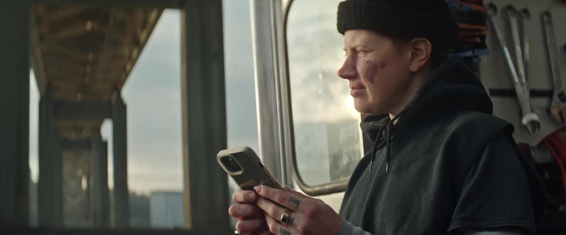 A woman sitting on her truck under her bridge smiles while on cell phone