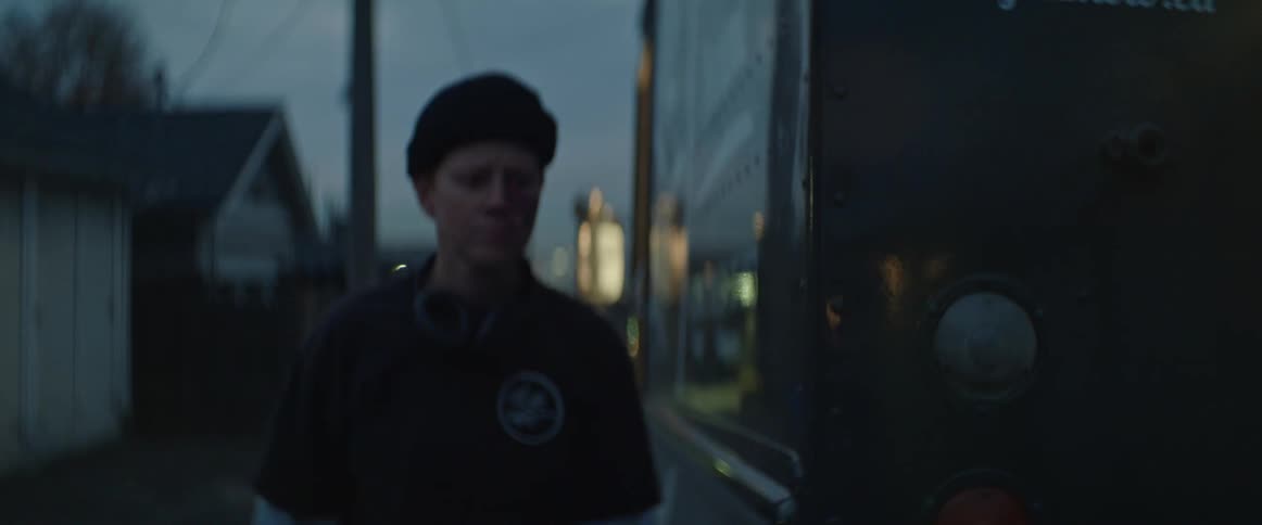 A person wearing a black hat gets out of a truck parked on the road