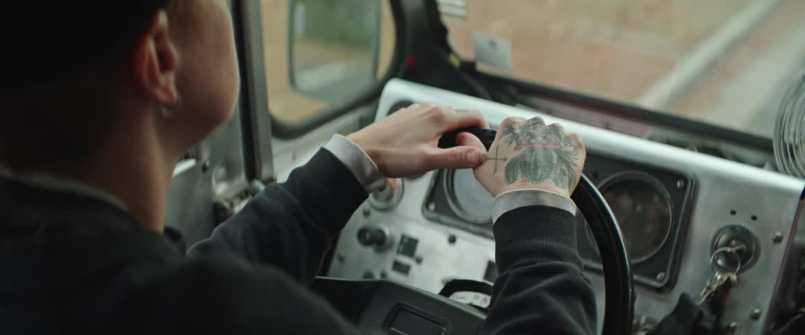 A person driving a vehicle with a tattoo on their right hand