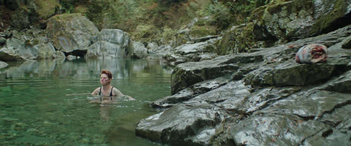 A woman swimming in a body of water in nature