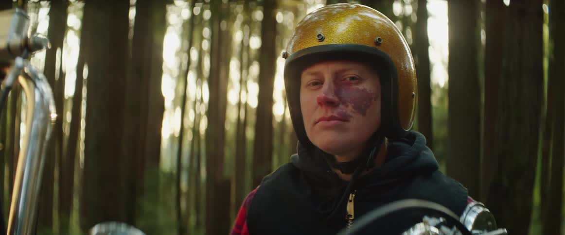 A woman is sitting on her motorcycle in the woods