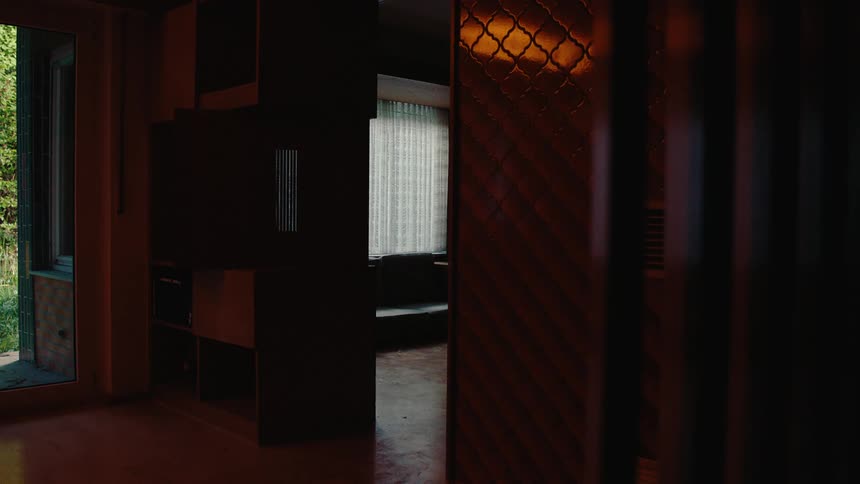 A dark room with windows in the background and a doorway on the left