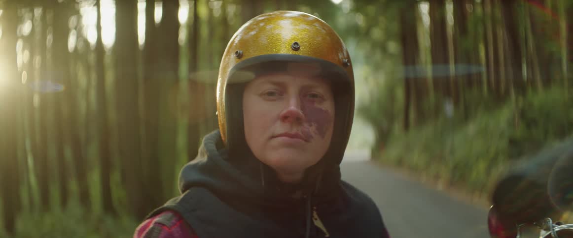 Portrait of a person sitting on a motorcycle wearing a yellow helmet and black hoody