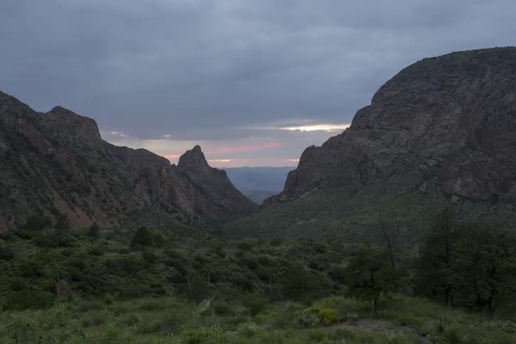 The sun rises behind mountains
