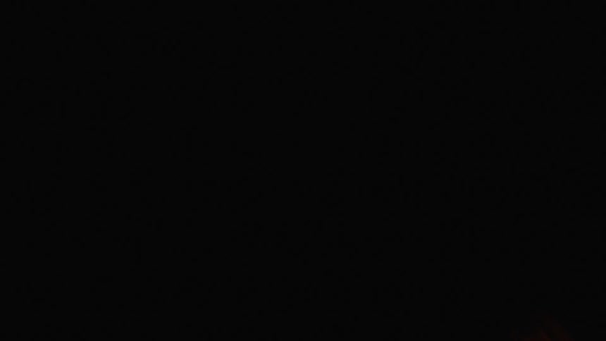 A glowing amber disk shines brightly in the darkness then vanishes in the night