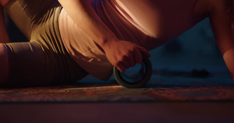 A woman using a foam roller as she stretches back and forth during floor exercise