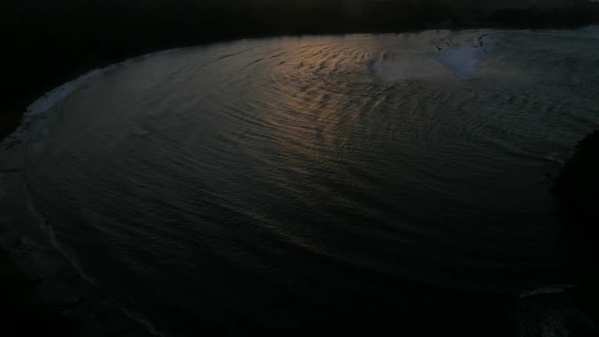 Waves washing ashore under a cloudy sky as night falls