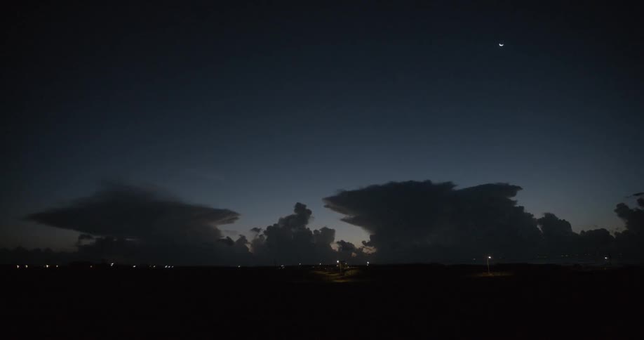Lightning flashes among thunder clouds in the dusk sky