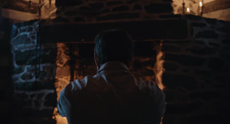 A man sits in front of a fireplace rocking back and forth